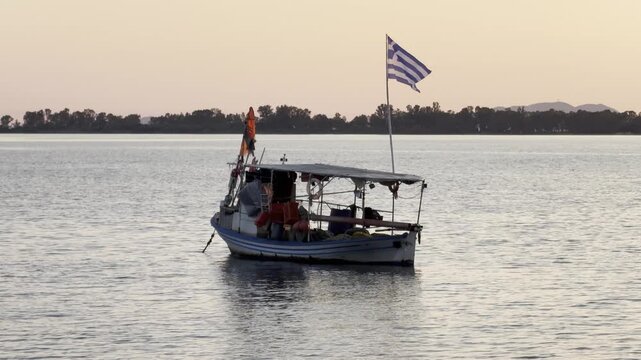 Calm evening video of a fishing boat flying the Greek flag while resting on the water in Igoumenitsa Greece.