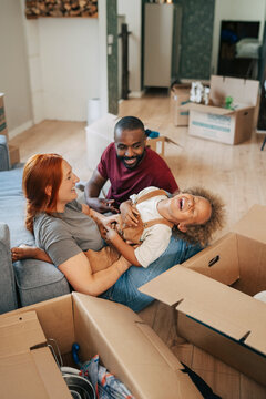 Parents tickling their son while sitting in living room during house relocation