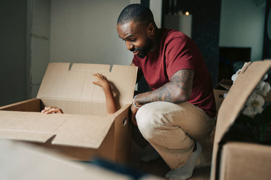 Happy father playing hide and seek with his child in moving box