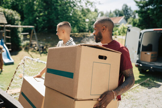 Father and son carrying moving boxes during house relocation