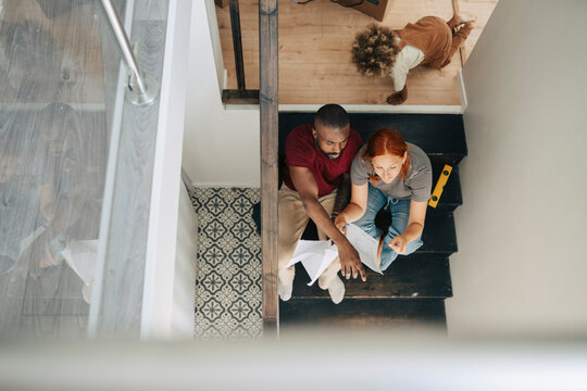 High angle view of diverse parents discussing house plan while sitting on steps