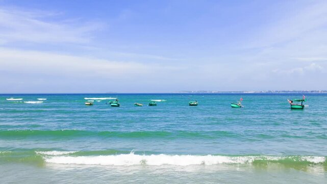 Bright sunlight shines over the sea at Mui Ne in Lam Dong. Local fishing boats move through the water. Gentle waves crash on the shore. This area is known for fishing activities.