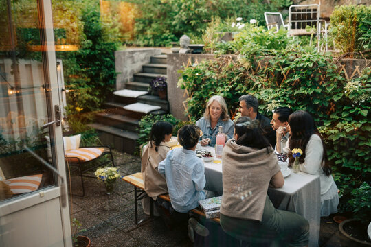 Multi-generational family celebrating dinner party at table in backyard garden