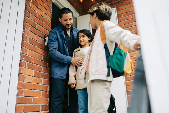 Father standing with his son and daughter at doorstep