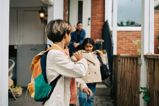 Boy looking over shoulder and waving goodbye to his father while leaving for school