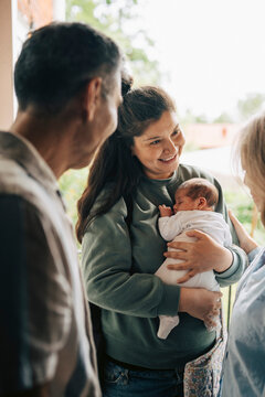 Smiling mother with newborn baby standing at doorstep