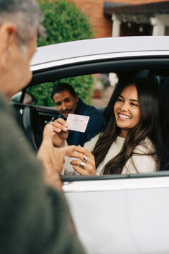 Happy woman showing her new driving license while sitting with instructor in car