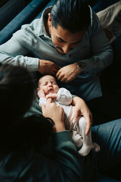 Directly above shot of parents with their newborn daughter sitting on sofa