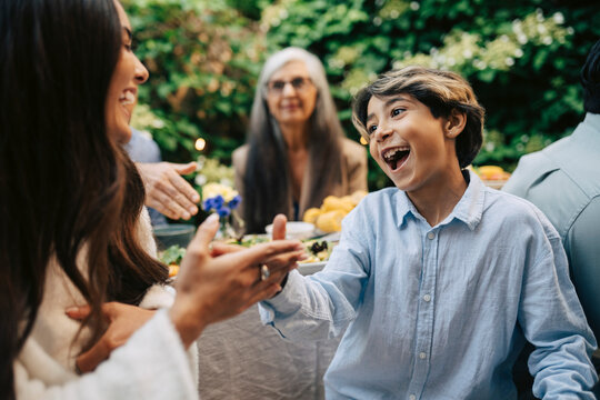 Happy boy playing with woman at outdoor family dinner party