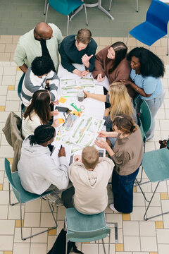 High angle view of multiracial high school students and teachers discussing about presentation of sustainability