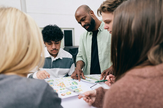 Male teacher helping students in making project at high school