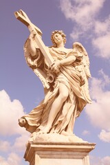 Fototapeta premium Angel in Rome, Italy. One of the angels at famous Ponte Sant' Angelo bridge. Baroque sculpture by Ercole Ferrata. Sunset light. Retro filtered colors photo style.