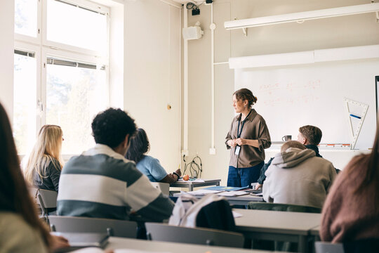 Female mathematics professor teaching teenage students in classroom at secondary school