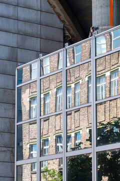Brick facade and structural framing meet in urban architecture showing layered materials windows and construction around an existing building in a close exterior detail