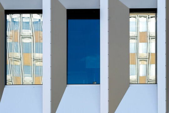 Minimal modern facade with blue window glass and white structural frames creating a clean geometric architecture pattern in a close architectural detail