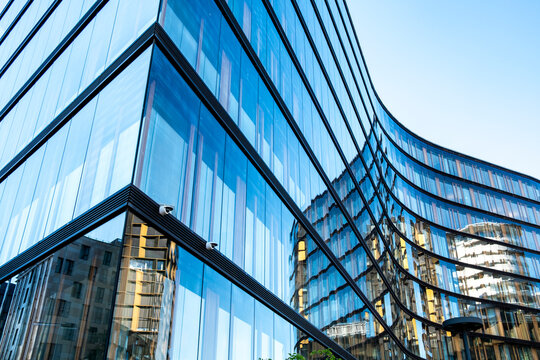 Curved blue glass architecture with reflective office facade and sharp corner geometry creates a modern urban perspective in a contemporary business setting