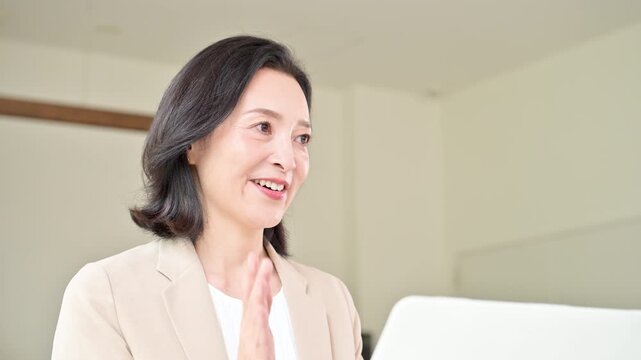 スーツを着て笑顔で顧客と対面相談する50代女性、オフィスで説明や提案を行うビジネスウーマン　コミュニケーションや商談などのビジネスイメージの動画
