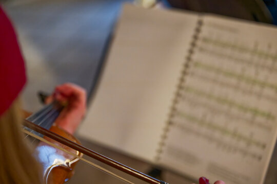 Person playing violin with music sheet in background in warm lighting