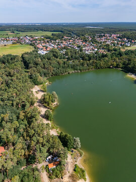 Aerial view of Pieskovna lake surrounded by dense pine forests with the village of Plavecky Stvrtok in the background, Plavecky Stvrtok, Bratislava Region, Slovakia.