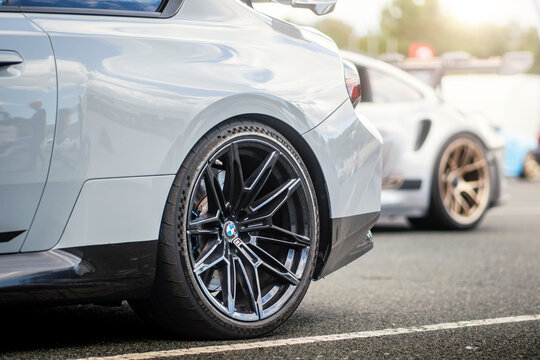 Brno - Czech Republic - September 2, 2026: Detail of the black rear wheel of a fast BMW sports car. A Porsche wheel is also visible in the background.