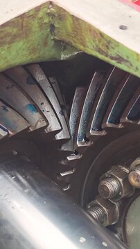 Heavy-duty spiral bevel gear assembly meshing together, featuring detailed teeth contact patterns with blue lubrication dye on the mechanical component. Industrial machine equipment part, close-up wit