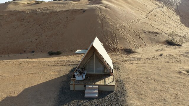 Aerial view of a luxury glamping tent set against the vast sand dunes of the desert in Muscat, Muscat Governorate, Oman.