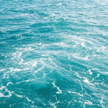 Pure blue turquoise water texture of the ocean sea with foam from and waves