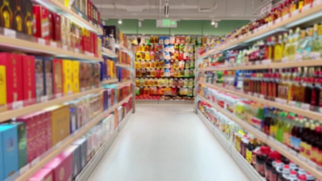 Long Supermarket Aisle Between Tall Shelves Filled with Various Products 