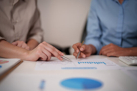 Close up of hands pointing at financial charts during business meeting