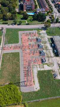 Aerial view of C.P. Seguro electrical substation with power pylons, transformers, and switchgear surrounded by green spaces and residential buildings in Settimo Milanese, Lombardy, Italy.