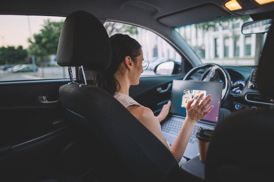 Businesswoman joining video meeting from back seat of car