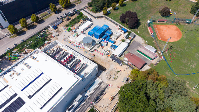 Aerial view of Data center MIL03 construction site with modular containers, industrial equipment, and solar panels on the roof in Castelletto, Lombardia, Italy.