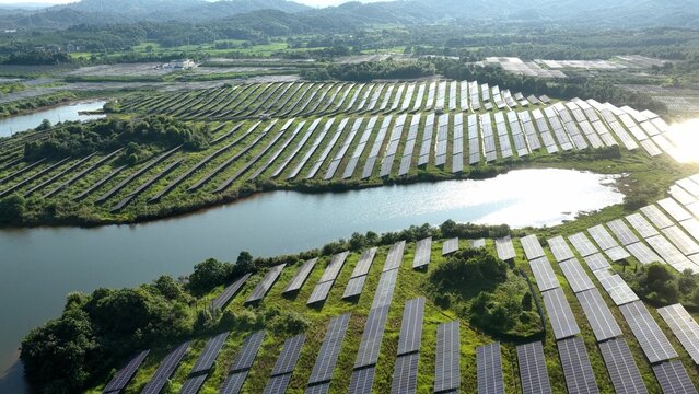 Solar panel array in green hills and water landscape
