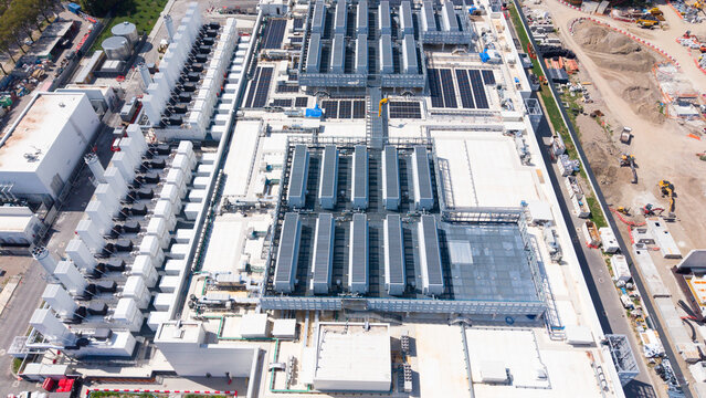 Aerial view of the Vantage VDC MXP2 data center facility featuring rows of cooling units, large white industrial buildings, and solar panels on the roof in Castelletto, Lombardia, Italy.
