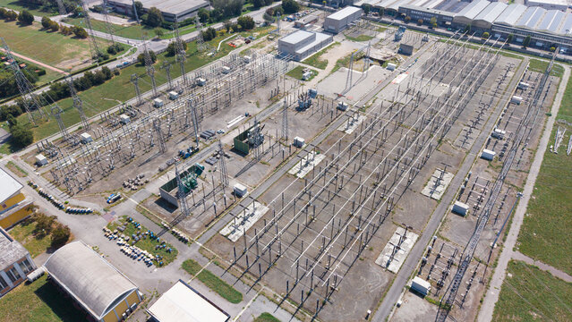 Aerial view of Terna Baggio electrical substation with complex power lines, metal structures, and transformers in an industrial area in Settimo Milanese, Lombardia, Italy.