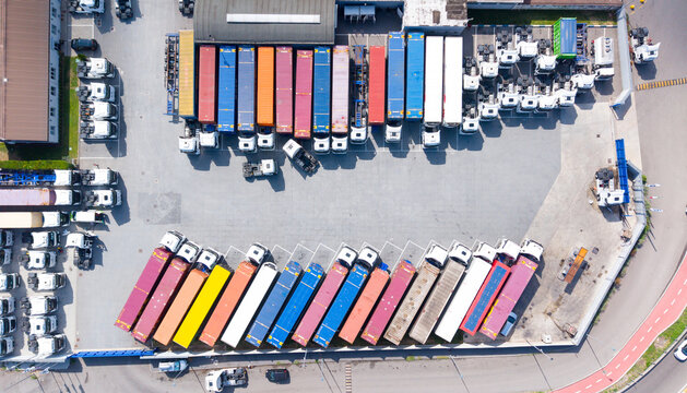 Aerial view of a logistics facility with rows of colorful freight trailers and trucks parked in a transport hub in Cusago, Lombardy, Italy.