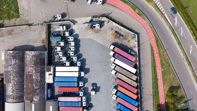 Aerial view of a logistics facility with rows of colorful freight trailers and trucks parked in a transport hub in Cusago, Lombardy, Italy.