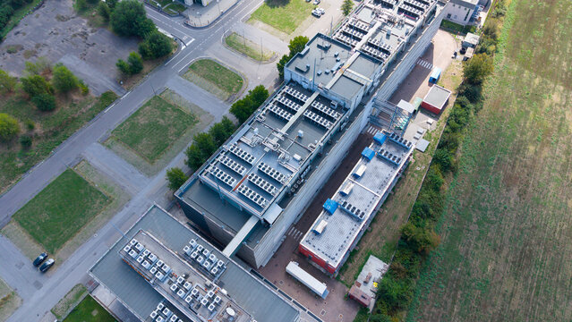 Aerial view of a modern data center facility with rooftop cooling units and surrounding infrastructure in Settimo Milanese, Lombardy, Italy.