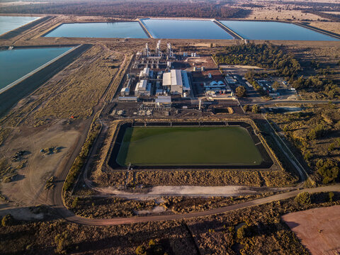 Aerial view of Kenya Central Processing Plant surrounded by large industrial water storage ponds and dry scrubland in the rural landscape Crossroads, Queensland, Australia.