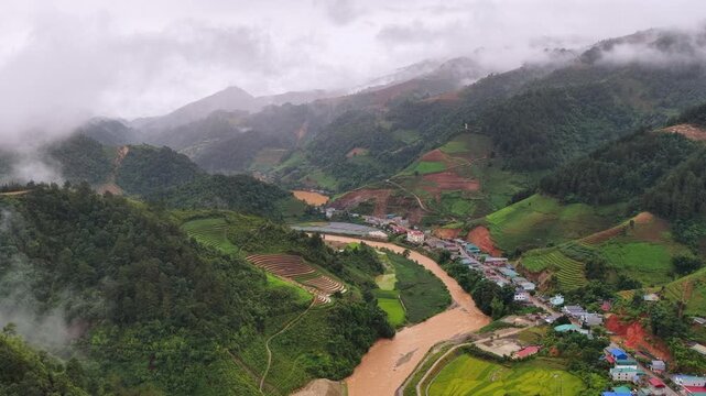 Aerial drone view of a river winding through the mountainous landscape and rice paddies of Mu Cang Chai, Vietnam.