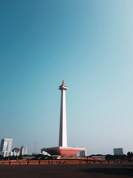 Tall white monas tower in jakarta, indonesia, against a clear blue sky on a sunny day.