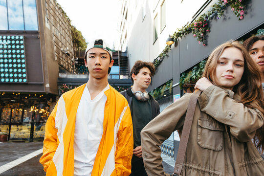 Group of male and female teenage friends walking together at street in city