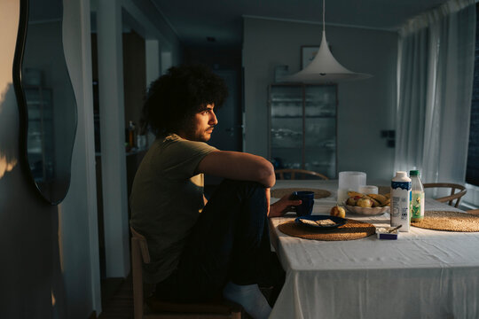 Side view of thoughtful man contemplating while sitting at dining table