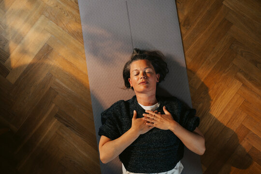 Directly above shot of woman taking deep breath during home yoga session