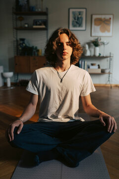 Full length of young man meditating during home yoga session