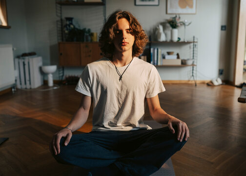 Young man practicing yoga while sitting on floor at home