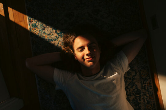 Directly above shot of smiling young man lying down on floor at home