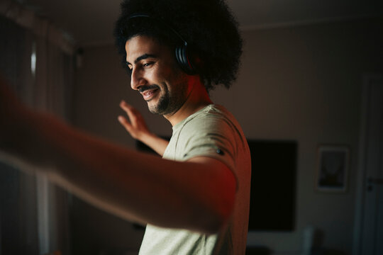 Happy man with curly hair dancing while listening to music at home