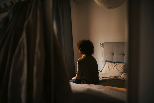 Depressed man sitting alone in bedroom at home