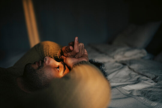 Thoughtful man lying down on bed at home